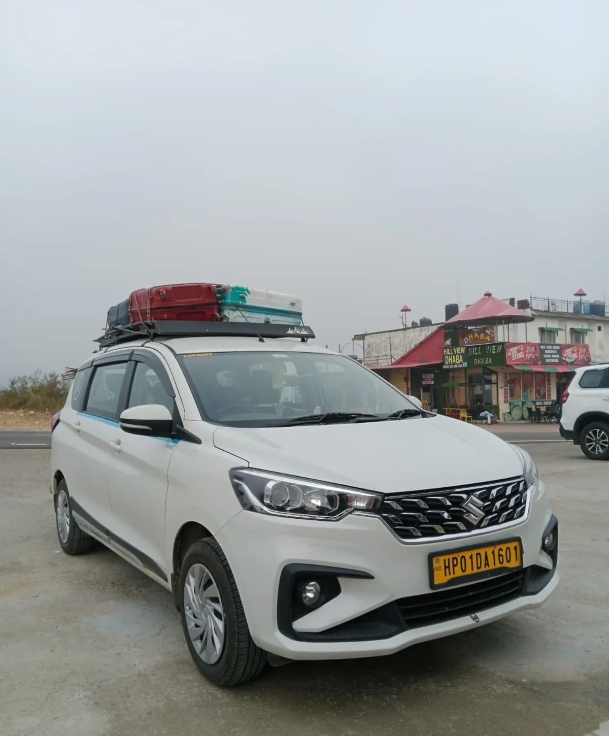 Our white Maruti Ertiga, HP 01 DA 1601, with suitcases on the roof carrier, parked outside a roadside dhaba
