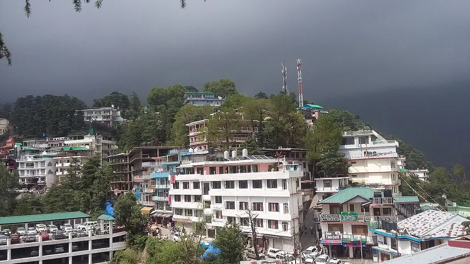 Hotels and houses packed along the ridge at McLeodganj under a dark sky
