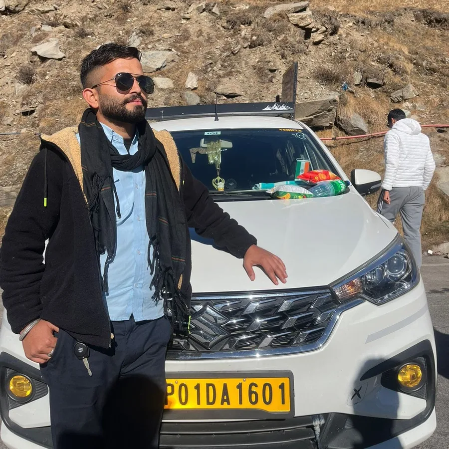 Sahil, owner and driver at Baglamukhi Travels, beside the Maruti Ertiga (HP 01 DA 1601) in the Himalayas
